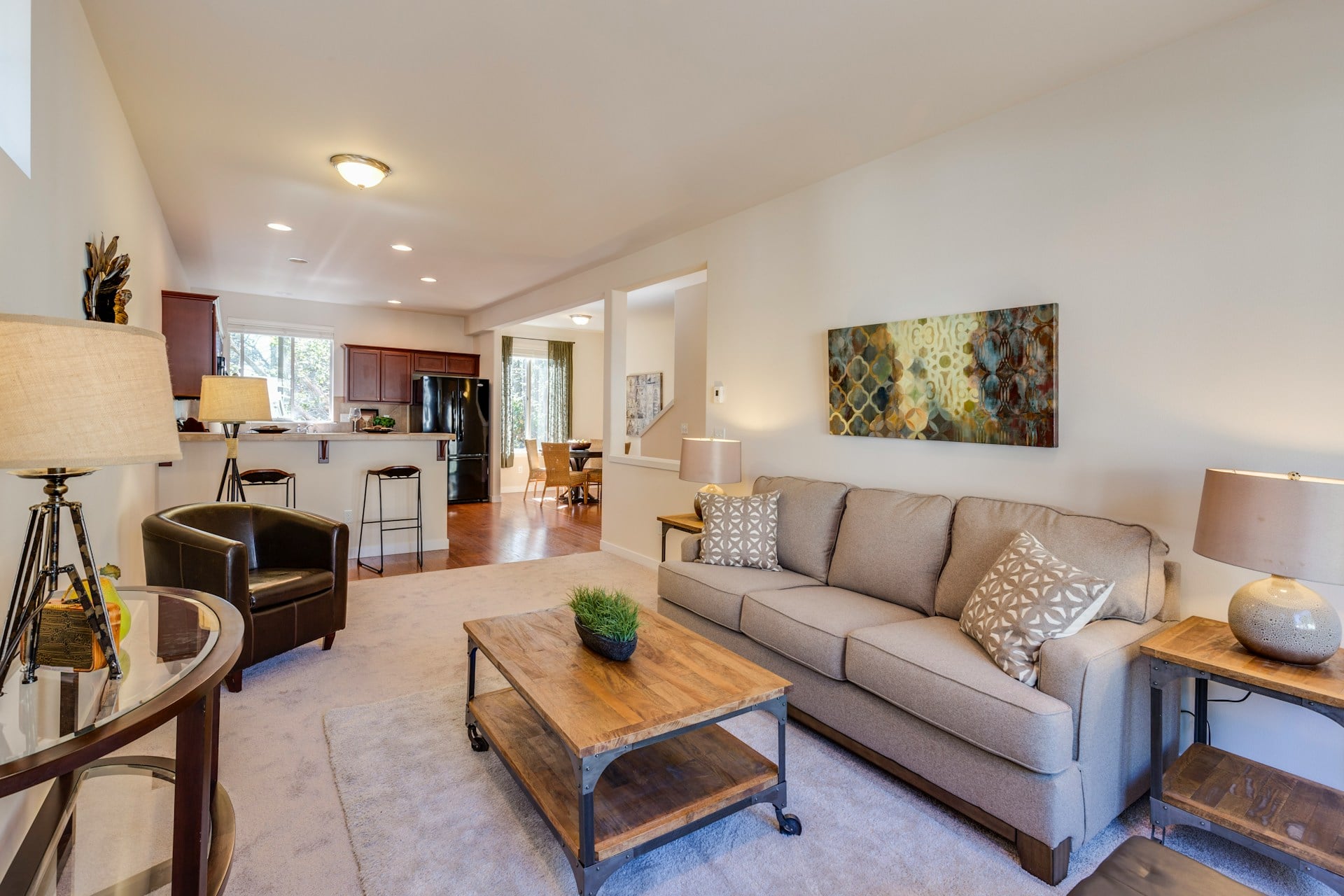 Living room with beige sofa, coffee table, and kitchen in the back
