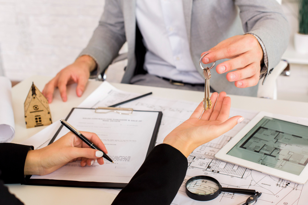 Person giving house keys over table with documents and tablet