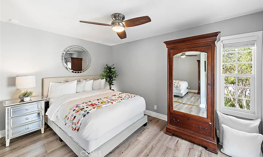 Bedroom with bed colorful pillows dresser and mirror