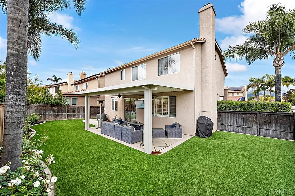 Backyard with grass covered patio seating grill and trees