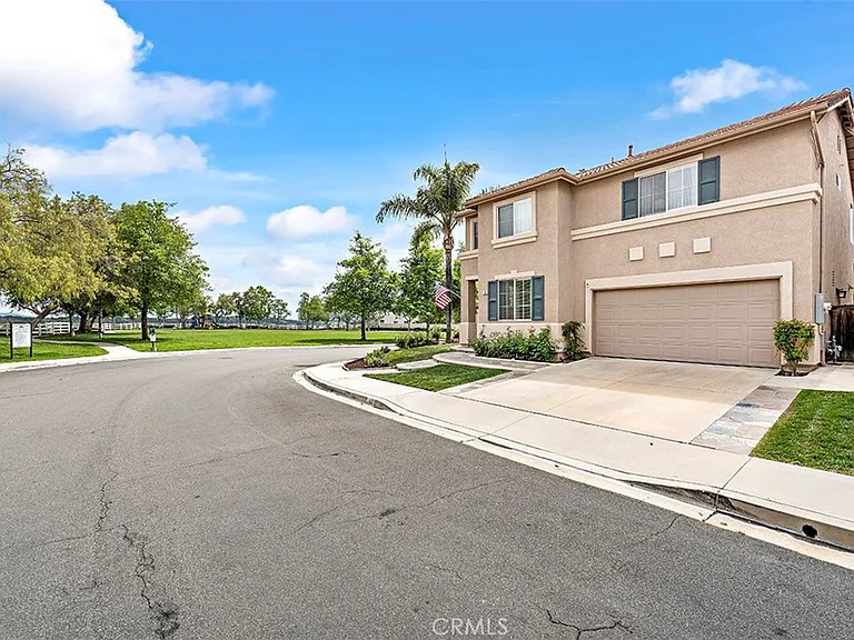 Corner California real estate house with tan exterior garage and green grass