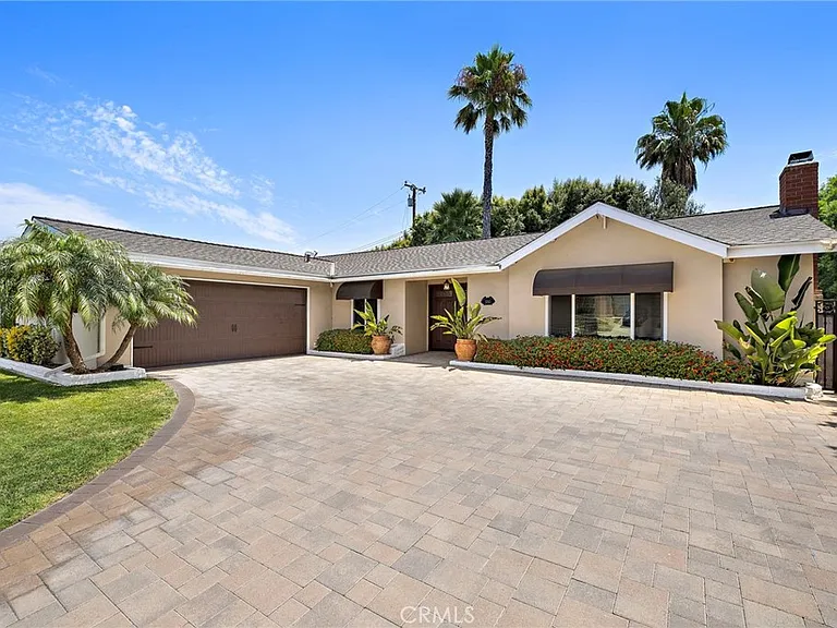 Single story California real estate house with driveway palm trees and garden