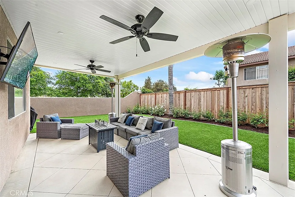 Covered patio with seating TV and landscaped yard