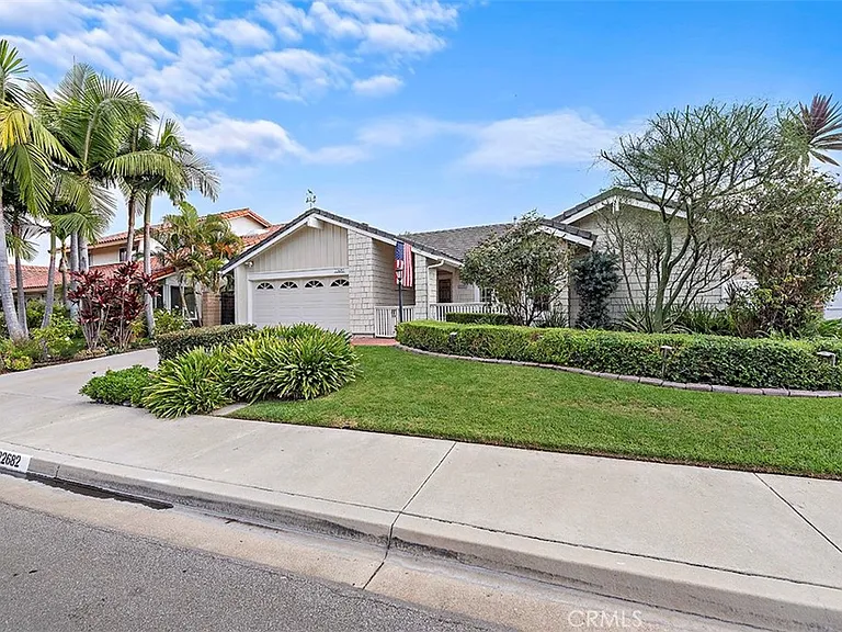 Single story California real estate house with lawn palm trees and shrubs