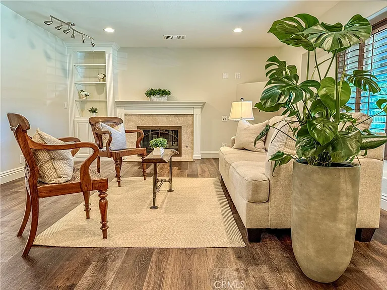 Living room with beige couch chairs fireplace and plant