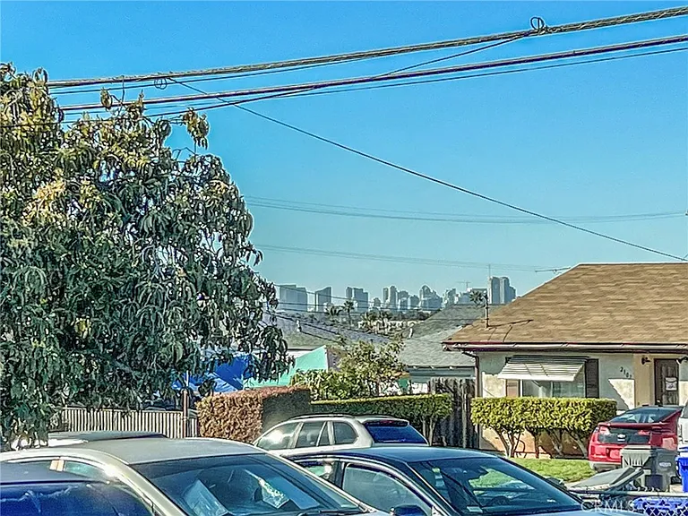 View of skyline with trees, power lines, and parked cars