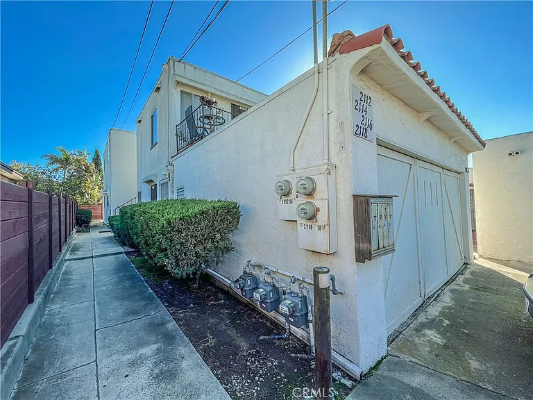 Pathway beside stucco building with garage door and shrub