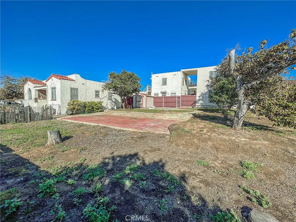 Backyard with paved area and California real estate house with trees and fence