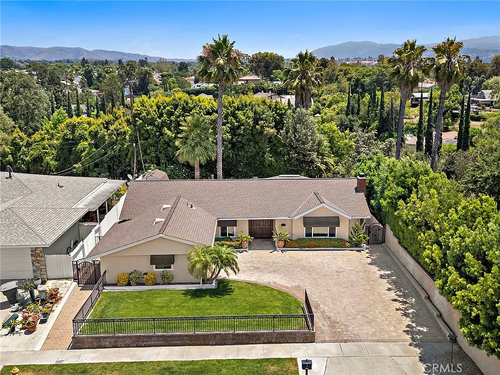 Single story California real estate house with front yard trees and palm trees