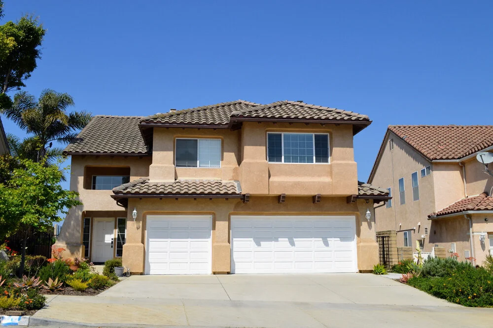 Two story California real estate house with tiled roof driveway garage and palm trees