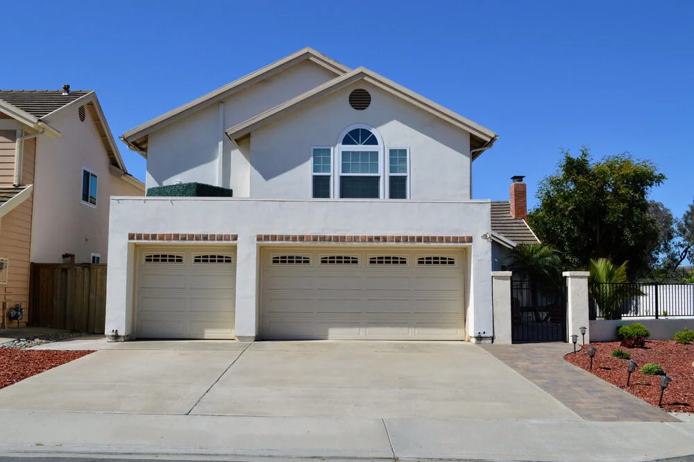 Two story California real estate house with three-car garage driveway and palm trees